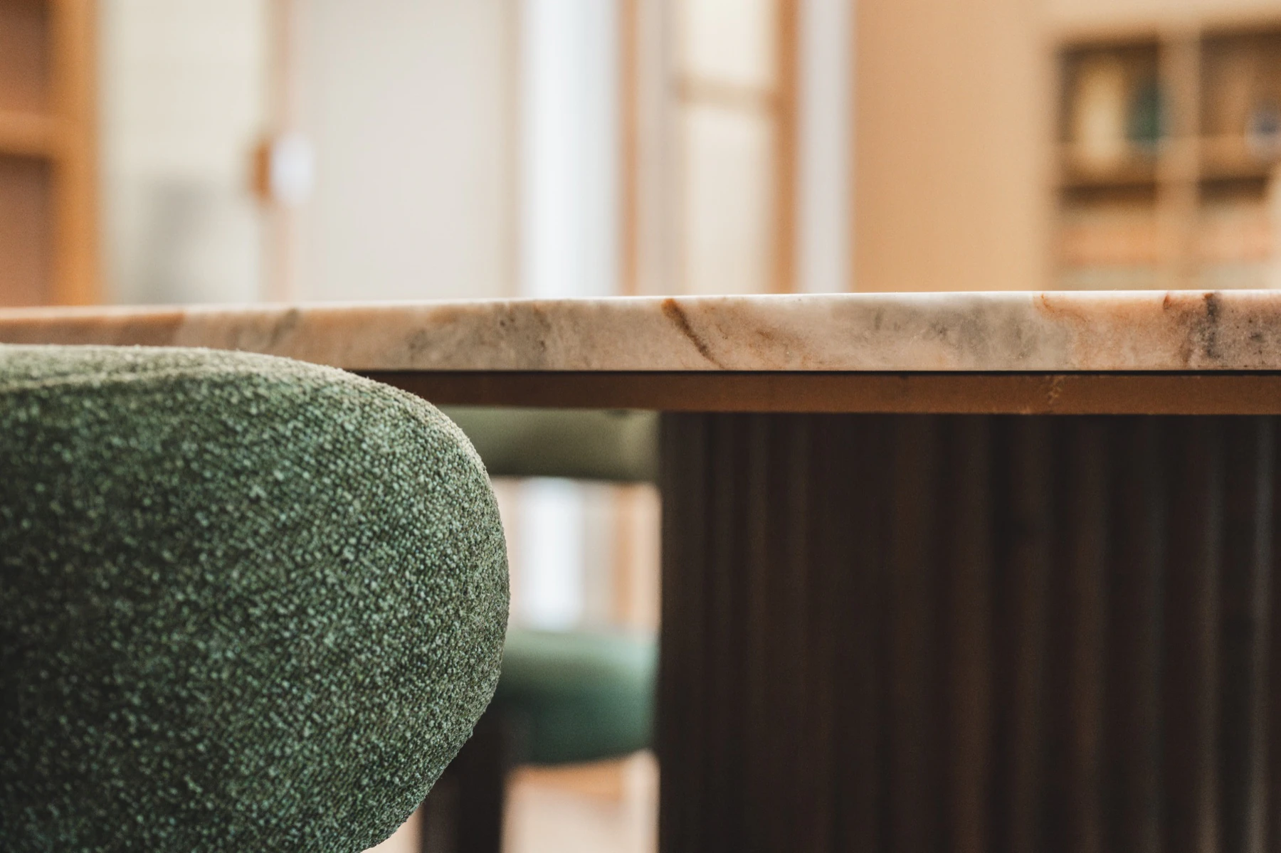 Detalle de la mesa de mármol y silla verde de la sala de reuniones
